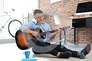 Happy young businessman playing guitar during break
