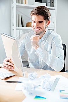 Happy young businessman reading notes in notpad