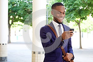 Happy young businessman reading text message on his mobile phone