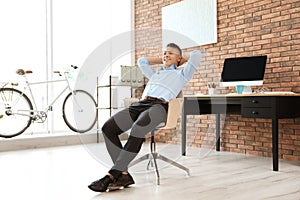 Happy young businessman relaxing in office