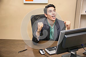 Happy young businessman screaming for joy, at desk