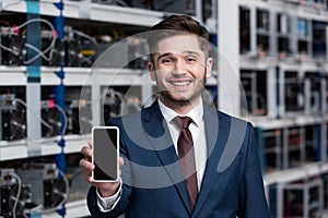 happy young businessman showing smartphone at cryptocurrency