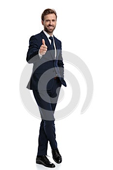 Happy young businessman smiling and making thumbs up sign