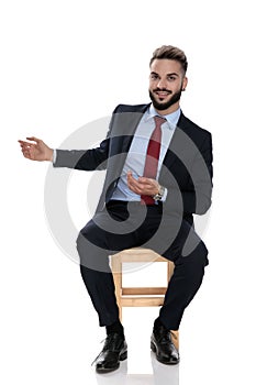 Happy young businessman smiling and presenting to side