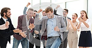 Happy young businessman standing in front of his business team.