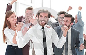 Happy young businessman standing in front of his business team