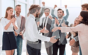 Happy young businessman standing in front of his business team