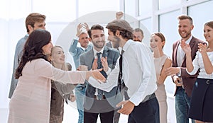 Happy young businessman standing in front of his business team