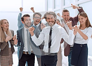 Happy young businessman standing in front of his business team