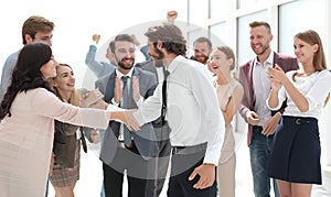 Happy young businessman standing in front of his business team