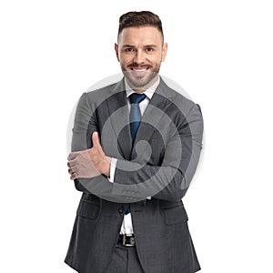 Happy young businessman standing with hands crossed is laughing