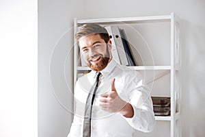 Happy young businessman with thumbs up gesture