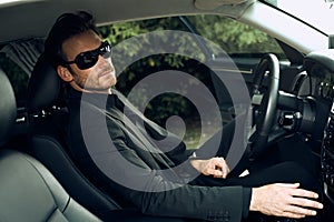 Happy young businessman traveling driving luxury car