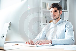 Happy young businessman using laptop computer in office