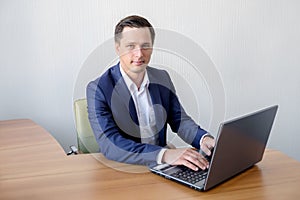 Happy young businessman using laptop at his office desk.