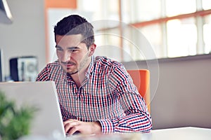 Happy young businessman using laptop at his office desk.