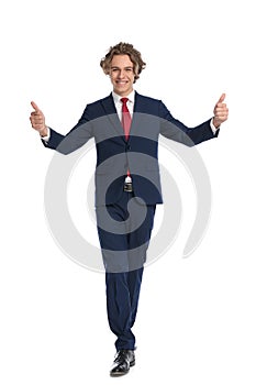 Happy young businessman walking and making thumbs up sign