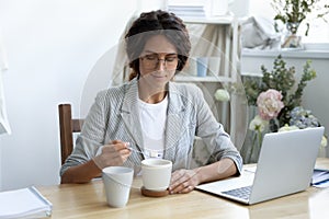 Happy young businesswoman adding refined sugar to cup of coffee.