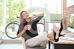 Happy young businesswoman with cup of coffee enjoying peaceful moment