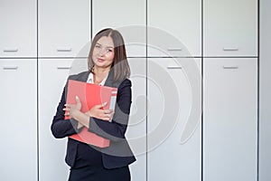 Happy young businesswoman holding a red binder And smiling