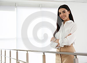 Happy young businesswoman leaning on railing in office. Space for text