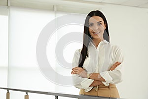 Happy young businesswoman leaning on railing in office. Space for text