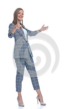 Happy young businesswoman pointing finger and presenting to side