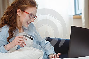 Happy young businesswoman using tablet pc in hotel room. Online shopping with credit card.
