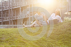 Happy young businesswomen with laptop on office lawn