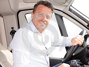 Happy young car driver behind steering wheel of van driving concept