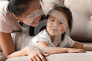 Happy young caring vietnamese mommy cuddling funny baby girl.