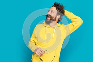 Happy young casual guy holding hand behind back and laughing