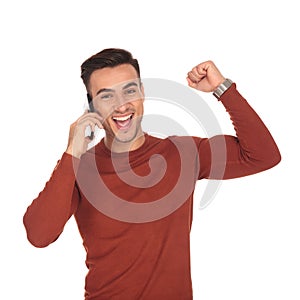 Happy young casual man celebrating good news on the phone