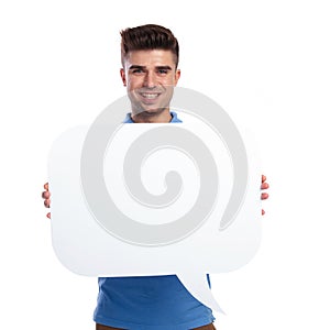 Happy young casual man holding a blanck speech bubble