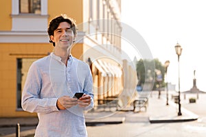 Happy young casual man holding mobile phone
