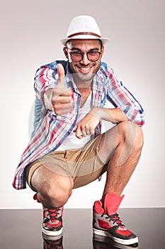 Happy young casual man showing the thumbs up gesture