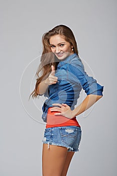 Happy young casual woman pointing at you, on gray background