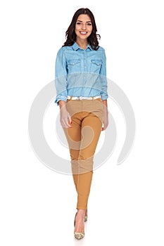 Happy young casual woman walking forward and smiles