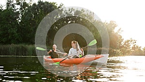 Happy young caucasian couple kayaking on river with trees in the background