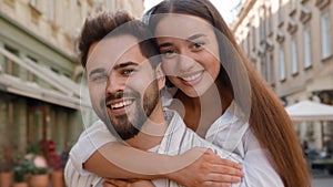 Happy young Caucasian couple man woman cuddling hugging hug embrace together love enjoy smile family honeymoon outside
