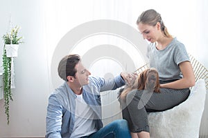 Happy young caucasian couple play with dog in home