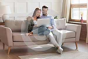 Happy couple relax on sofa using laptop together photo