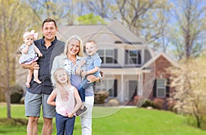 Happy Young Caucasian Family Outside  In Front of Their New Home