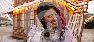 Happy young caucasian girl laughing with teeth and closed eyes spends leisure time in park.