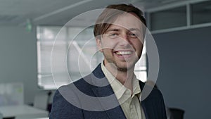 Happy young caucasian man in businesswear smiling and looking at camera in office