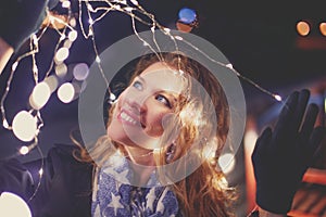 Happy young caucasian woman holding christmas LED lighs outdoor
