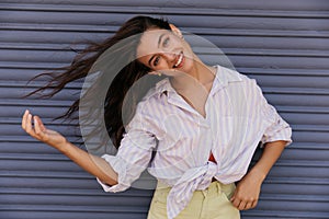 Happy young caucasian woman looking wide smiling at camera waves her hair outdoor.