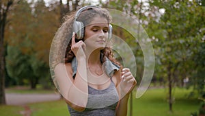 Happy young Caucasian woman put on wireless modern headphones earphones. Runner jogger girl sport female run running in