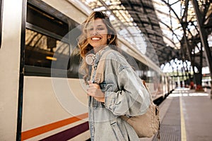 Happy young caucasian woman smiles with teeth looking at camera going on train trip.