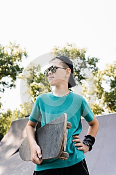 Happy young child boy with skate board on playground and smile. Extreme sport lifestyle. Smiling child with skate board